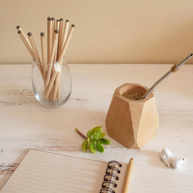 A close-up of eco-friendly office supplies on a wooden desk, including a bamboo pen holder, recycled paper notepad, and a small succulent plant. The focus is on the natural and sustainable materials used.