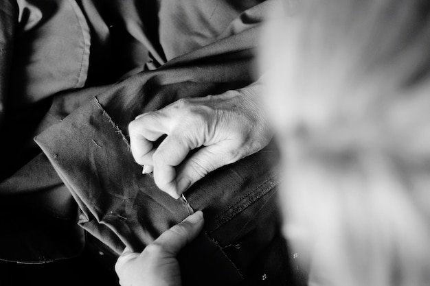 A close-up of a garment worker's hands meticulously sewing a piece of clothing in a well-lit, ethical factory. The focus is on the craftsmanship and the worker's dedication to quality.