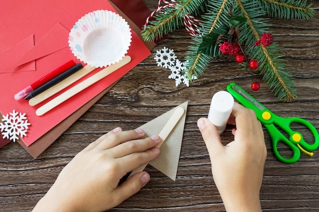 A close-up shot of hands crafting Christmas ornaments from recycled paper, with visible instructions and supplies like scissors and glue nearby. The setting is a well-lit craft room or kitchen.