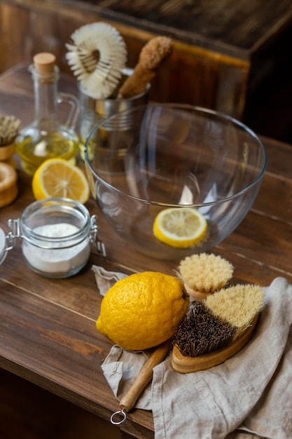 A close-up shot of ingredients commonly used in DIY cleaning solutions, such as baking soda, white vinegar, lemons, and essential oils, displayed in glass containers and arranged on a wooden surface.