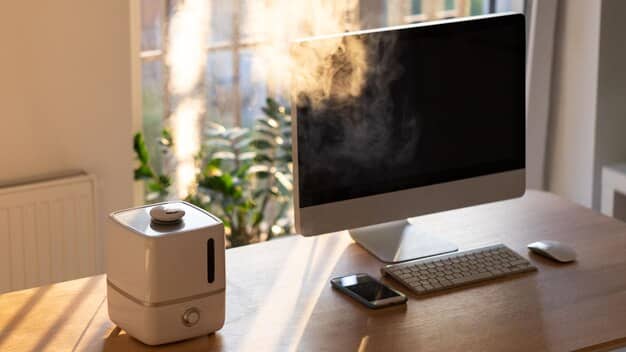 A home office setup with a focus on air quality, featuring an air purifier, several potted plants, and open windows allowing fresh air to circulate. The room looks clean, well-ventilated, and conducive to healthy indoor air quality.